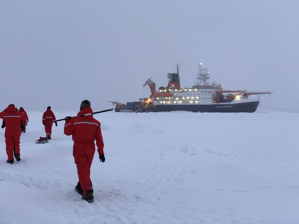 Scientists and ice breaker in Arctic ice flow.